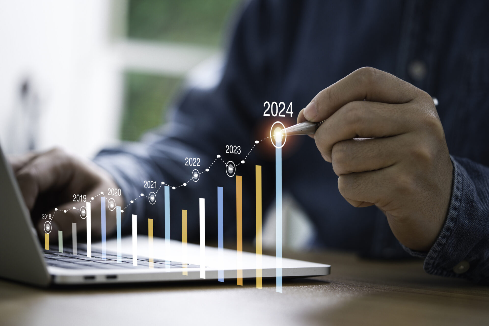 A person analyzes growth chart on a laptop, pointing to projected 2024 data. Charts show annual progress from 2018 to 2024.