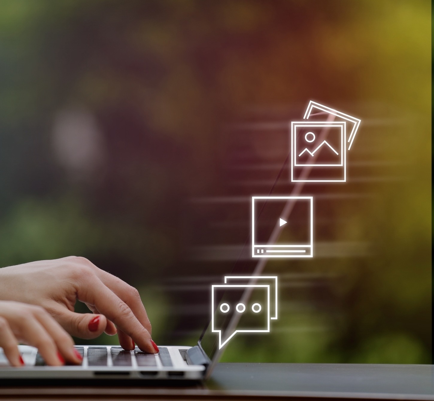 A person typing on a laptop with floating icons of images, videos, and messages, set against a blurred nature background.