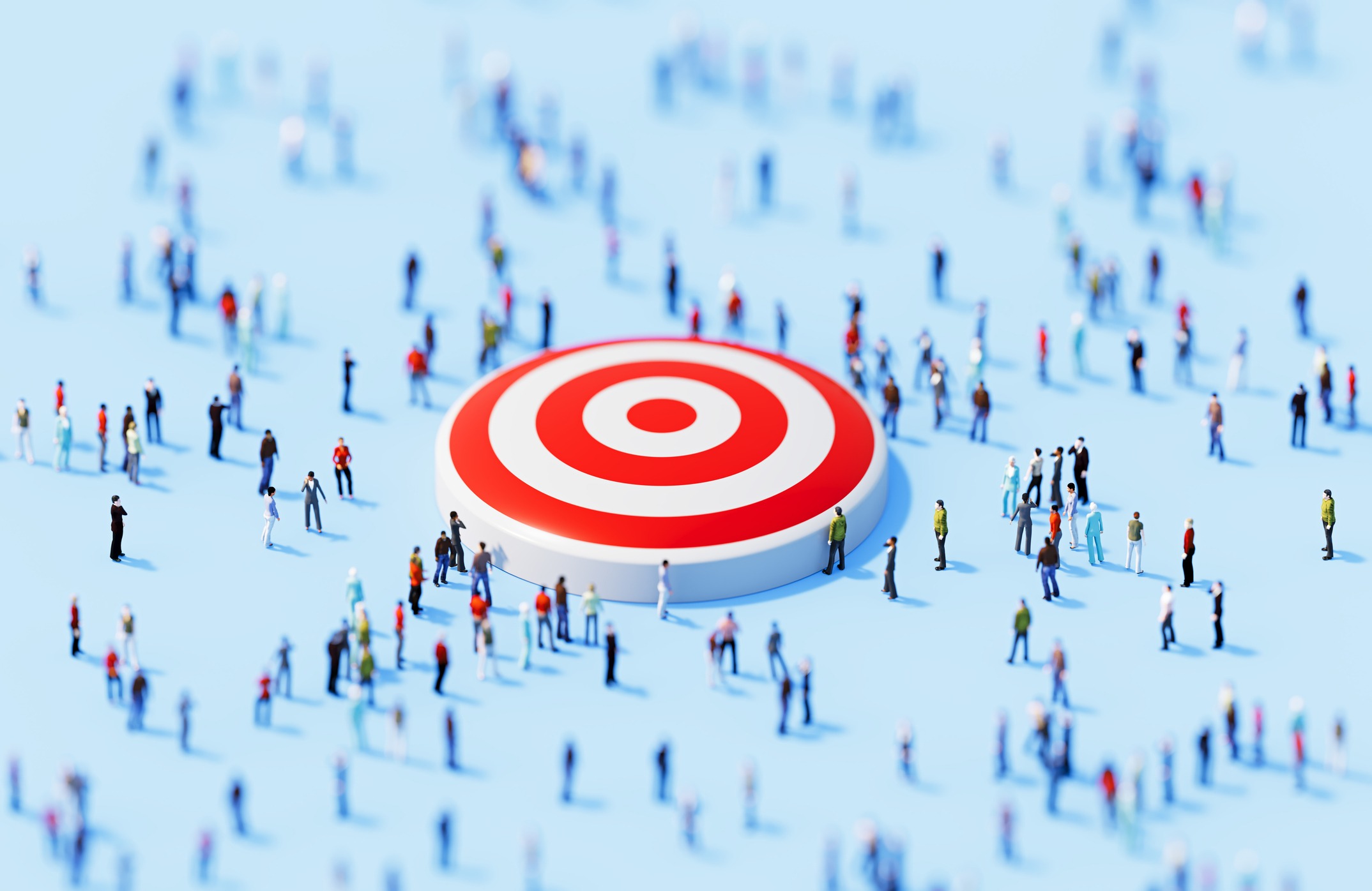 Numerous people gathered around a large red and white target on a light blue background, creating a dynamic and busy scene.