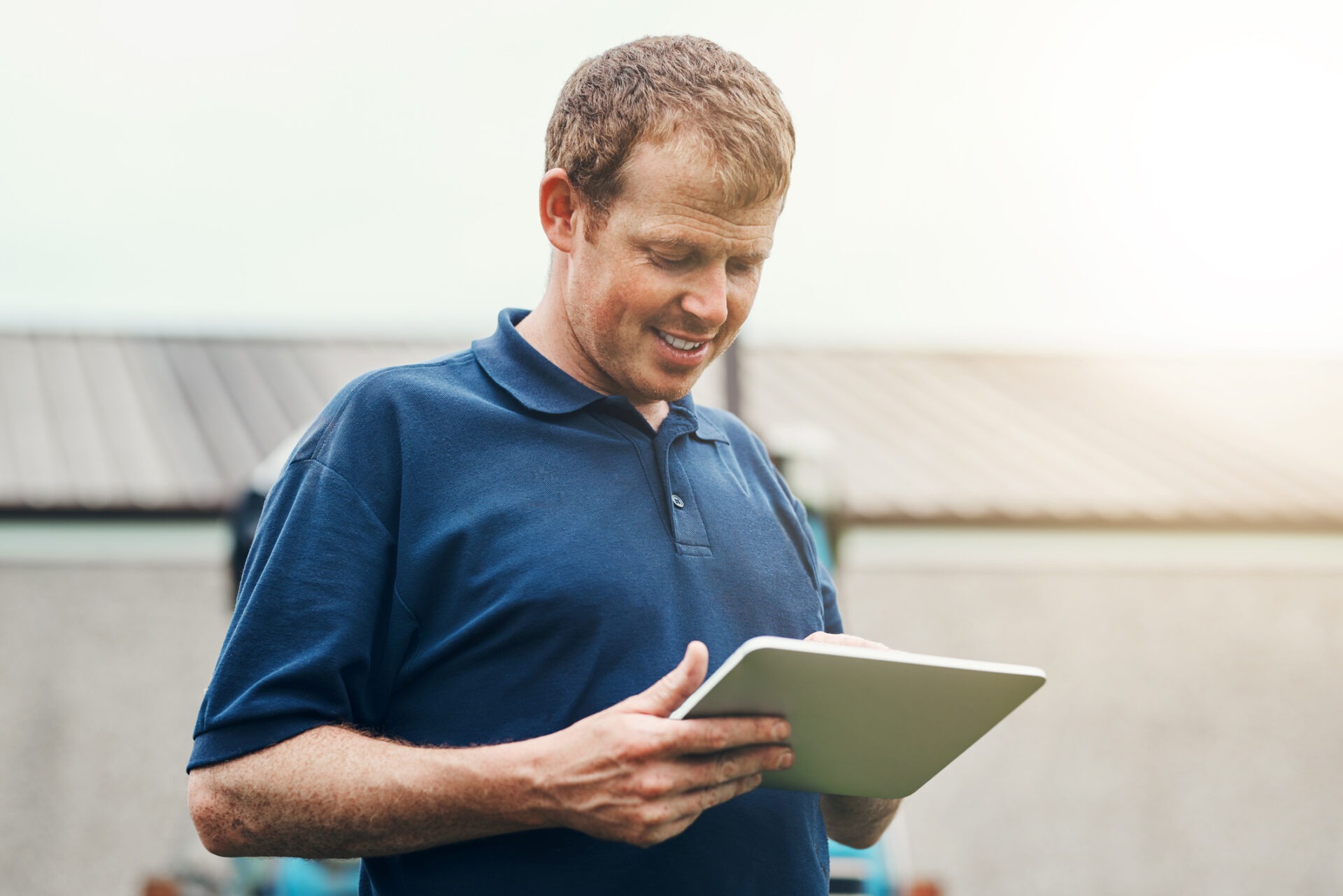 Shot of a cheerful young male farmer holding a digital tablet while standing outside on his land