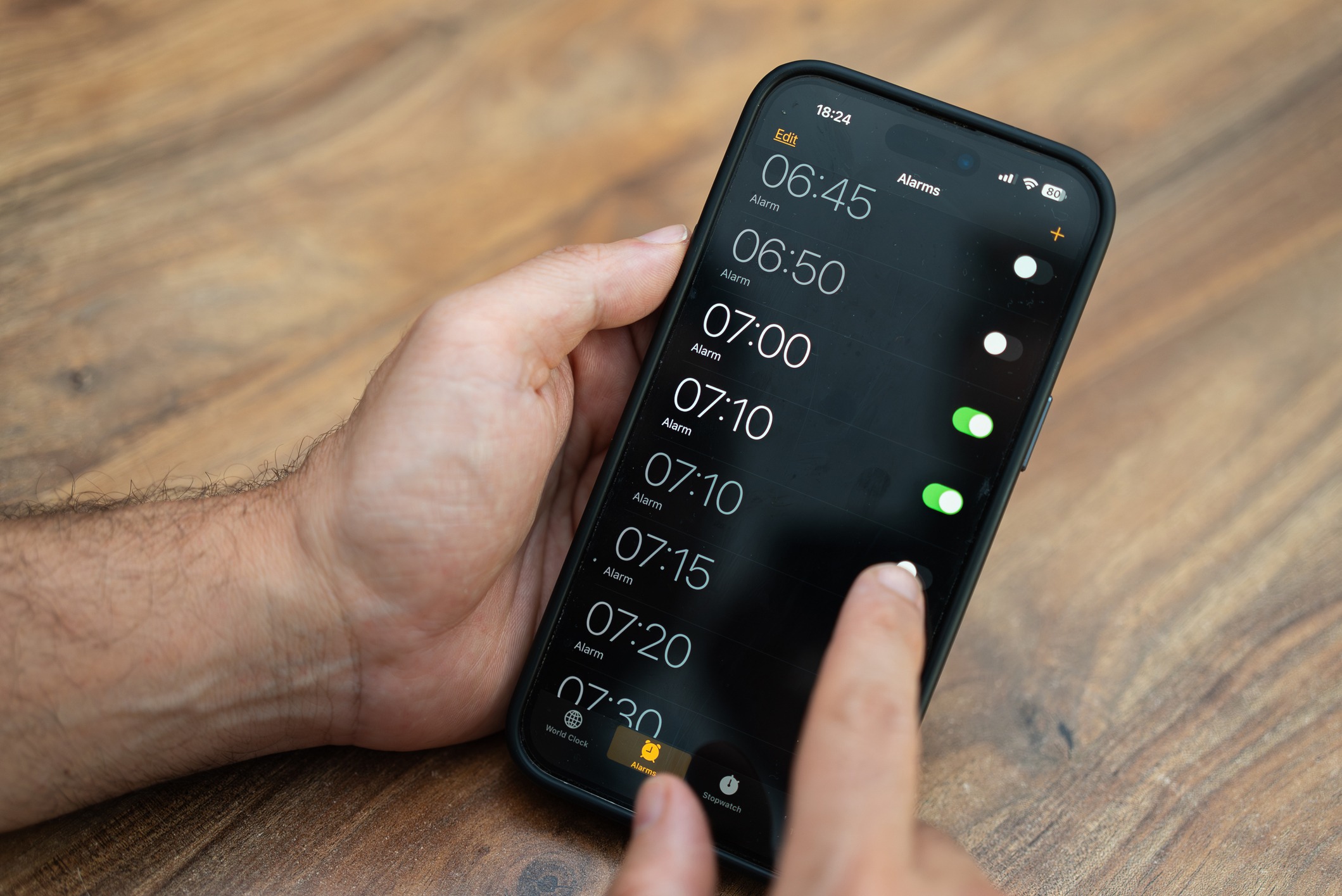 Person holds smartphone setting time on alarm clock app ensuring to receive notifications to wake up