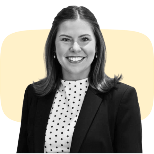 A black-and-white photo of a smiling person with long, straight hair wearing a dark button-up shirt against a backdrop with a light yellow shape.